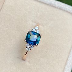 an engagement ring with a blue stone surrounded by white and clear stones in a box