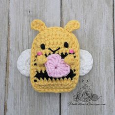 a crocheted cell phone case with a bear holding a flower in it's mouth