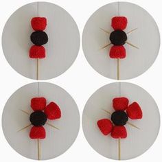 four red and black flowers are placed on a white plate with toothpicks in the middle