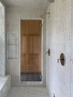 a white tiled bathroom with wooden doors and shelves on the wall, along with marble tile flooring