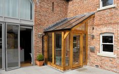 an outside view of a brick building with glass doors and a small wooden structure on the side