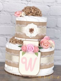 a three tiered wedding cake with pink flowers on the top and monogrammed ribbon