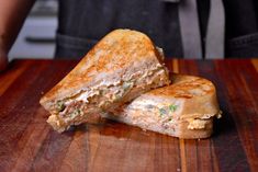 two grilled sandwiches sitting on top of a wooden cutting board