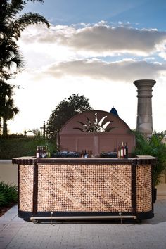 an outdoor bar with bottles on it in front of a building