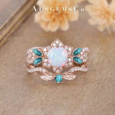 an opal and diamond ring is shown on a wooden surface with flowers in the background