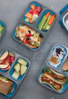 four plastic containers filled with food on top of a cement floor next to a bowl of fruit