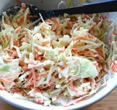 a white bowl filled with coleslaw on top of a wooden table