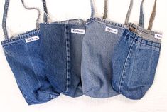 three pairs of jeans hanging from hooks on a white wall, with the back pocket open