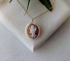 "A beautiful big size pendant and brooch carved on real cameo, tied a lot of 18k solid gold ! It's decorated with real white pearl around Its theme is \"A little cute Angel playing music\". It is completely hand made down to the last detail and it can easily be wear as a pendant and as a brooch It is the perfect gift for a lady who loves fine jewelry The dimensions of the pendant are height 1.18 inch(30mm) and width 0.79 inch(20mm) The chain IS NOT included in the price. Along with a beautiful g Cameo Pendant Jewelry For Memorial, Cameo Pendant Brooch For Wedding, Cameo Pendant Brooches For Wedding, Real Ruby Necklace, Cute Angel, Handmade Jewel, Greek Jewelry, Gold Pin, Vintage Cameo