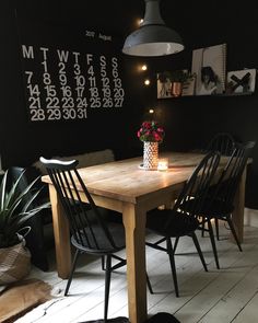 a dining room table with four chairs and a calendar on the wall behind it,