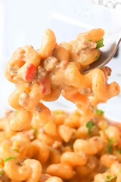 a spoon full of macaroni and cheese being held up