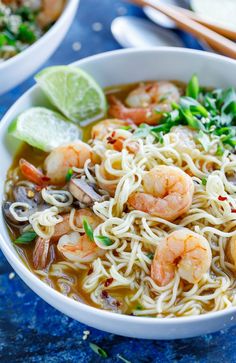 a bowl of shrimp noodle soup with chopsticks and lime wedges on the side