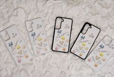 three cell phones are laying on a white surface and one has an iphone case with embellishments