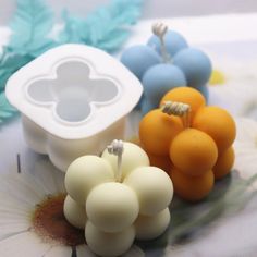 three small fruit shaped candles sitting on top of a table next to flowers and leaves