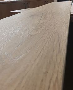 a close up of a wooden table in a room with other wood furniture and windows