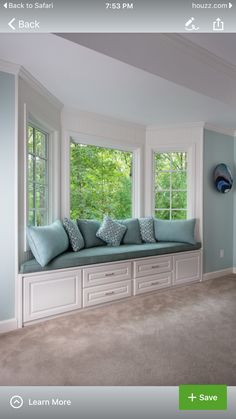 a window seat in the corner of a room with blue pillows and throw pillows on it