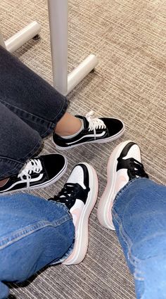 two people sitting at a table with black and white sneakers on their feet in front of them