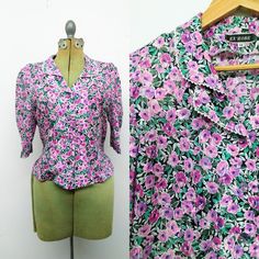 "Sweet vintage button down shirt with a rounded collar trimmed in lace. Light purple and teal floral top with clear purple rhinestone buttons  Slightly puffed half sleeves.  No material tag. Feels like poly cotton blend. Brand: Ex'Robe Size 12 Measures approx. 20\" armpit to armpit and 20.5\" long down the back Great vintage condition!" Vintage Purple Top For Spring, Purple Short Sleeve Button Blouse, Purple Short Sleeve Blouse With Buttons, Vintage Purple Tops With Buttons, Vintage Purple Tops With Button Closure, Purple Short Sleeve Blouse For Daywear, Vintage Short Sleeve Blouse For Vintage Fashion, Vintage Purple Top With Floral Print, Vintage Purple Floral Print Top