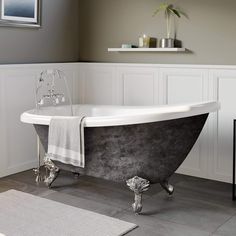 an old fashioned claw foot bathtub in a bathroom with gray walls and flooring