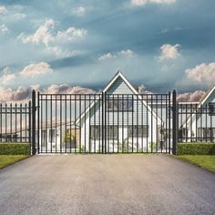 a gated driveway leading to two large white houses in front of a cloudy sky