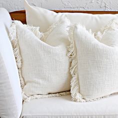 two white pillows sitting on top of a couch