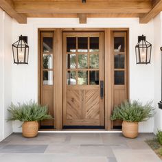 two planters on the front porch of a house with wooden doors and windows,