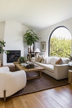 a living room filled with furniture and a fire place in front of a large window