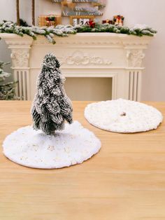 a small christmas tree sitting on top of a table next to a white fire place cover