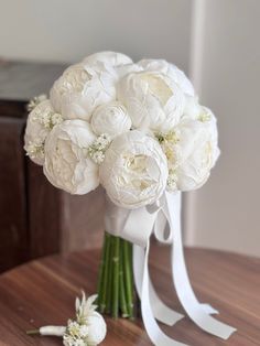 a bouquet of white flowers sitting on top of a wooden table