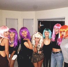 a group of young women standing next to each other in front of a door with bright colored hair