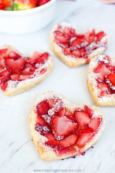 strawberry shortbreads with powdered sugar in the shape of hearts on a table