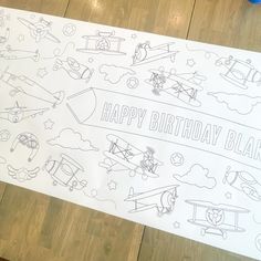 a birthday banner with airplanes and planes drawn on it, sitting on a wooden floor