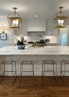 a kitchen island with four stools in front of it and two hanging lights above