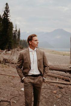 a man wearing a suit and tie standing in the dirt