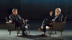 two men sitting in chairs talking to each other