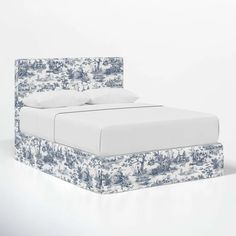 a bed with blue and white floral print on the headboard is shown in this image