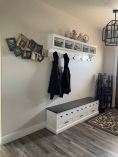 a coat rack with two coats hanging on it next to a bench in a room