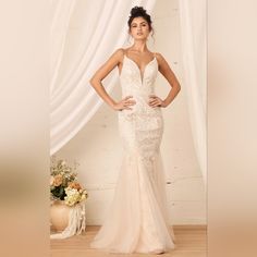 a woman in a wedding dress standing next to a white wall with flowers on it