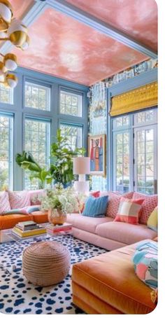 a living room filled with lots of furniture and large windows covered in colorful paint on the ceiling