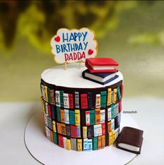 a birthday cake decorated with books and a happy birthday sign