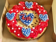 a cookie decorated with red, white and blue icing is in a cardboard box