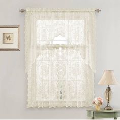 a window with white lace curtains and a lamp