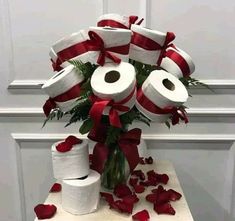 a vase filled with toilet paper on top of a table next to red rose petals