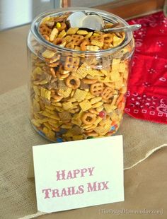 a jar filled with happy trails mix next to a sign