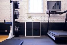 a room with black and white tiles, treadmills, television and cabinets in it