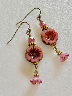 "Lovely little pink dangles featuring 15 mm pink Czech glass Hawaiian flowers with rustic Picasso glaze, 6 x9 mm fuchsia pink Czech bellflowers with copper, and 6 mm pink/gold fire polished crystal rondelles. Czech beads are accented with antique gold beaded spacers and daisies. Vintage bronze French ear hooks. Total drop 2\"." Hawaiian Aesthetic Outfit, Pink And Gold Earrings, Flower Clothes, Glass Flower Earrings, Pink Flower Earrings, Earring Beads, Flowers Earrings, Pink Jewels, Glass Bead Earrings