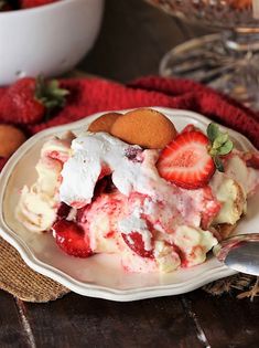 a white plate topped with strawberry shortcakes and ice cream next to a bowl of strawberries