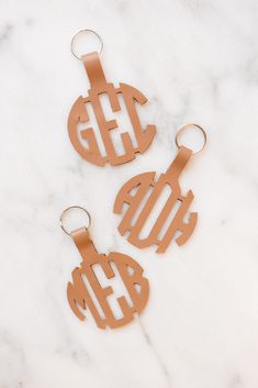 two metal monogrammed key chains on a marble surface