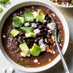 two bowls filled with black beans and avocado on top of a white table