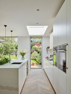 a kitchen with white cabinets and an open door leading to a garden area that overlooks the backyard